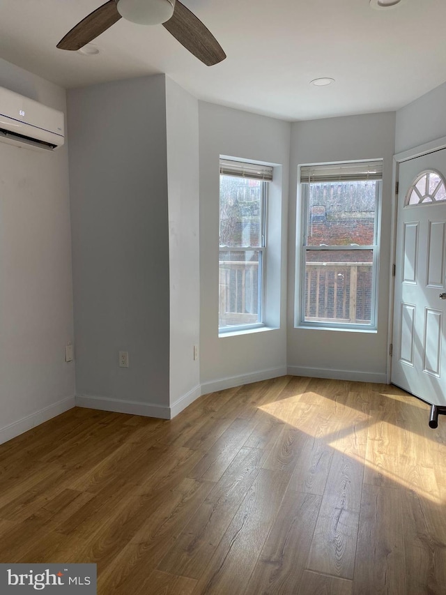 foyer featuring a wall mounted air conditioner, ceiling fan, and light hardwood / wood-style flooring