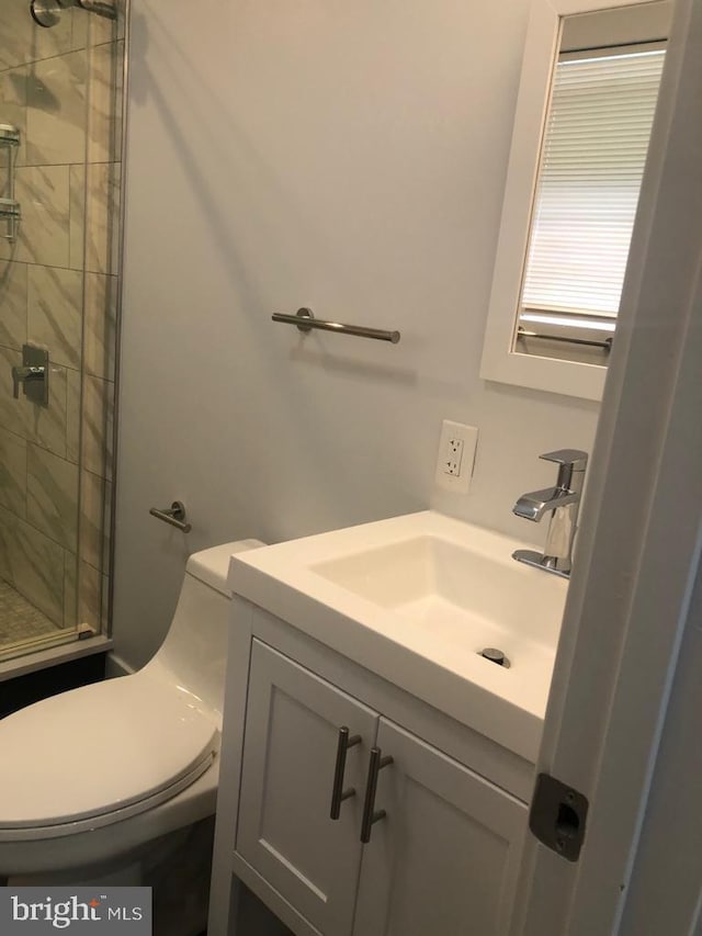 bathroom featuring walk in shower, vanity, and toilet