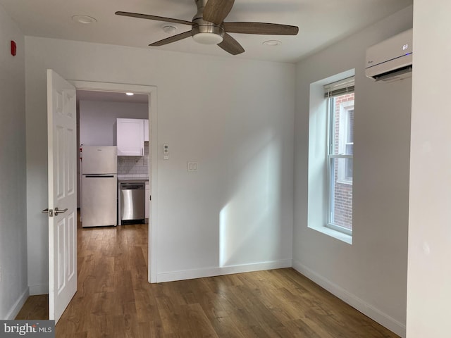 empty room with hardwood / wood-style floors, a wall unit AC, and ceiling fan