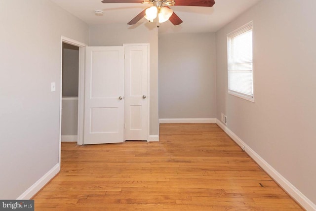 unfurnished bedroom featuring ceiling fan, a closet, and light wood-type flooring