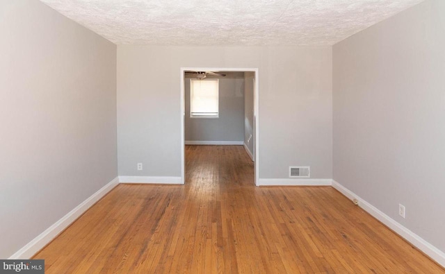 spare room featuring light hardwood / wood-style flooring and a textured ceiling