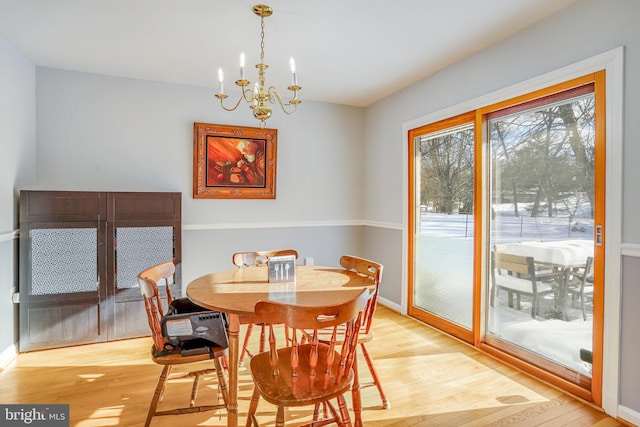 dining space with light hardwood / wood-style flooring and an inviting chandelier