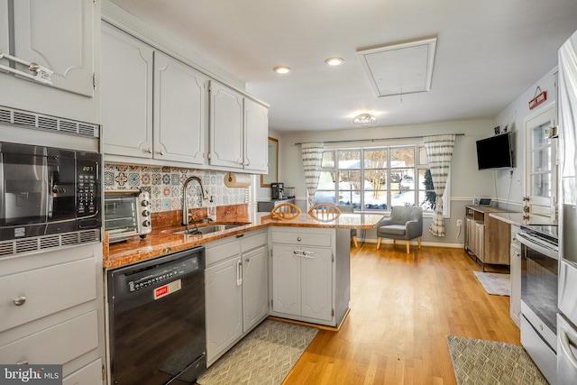 kitchen with kitchen peninsula, white cabinets, sink, dishwasher, and stainless steel microwave