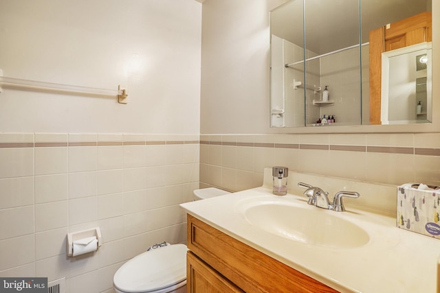 bathroom with vanity, toilet, and tile walls