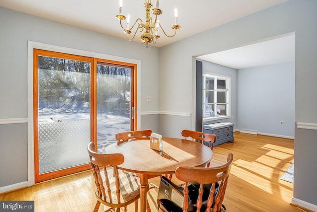 dining space with light hardwood / wood-style flooring and a chandelier