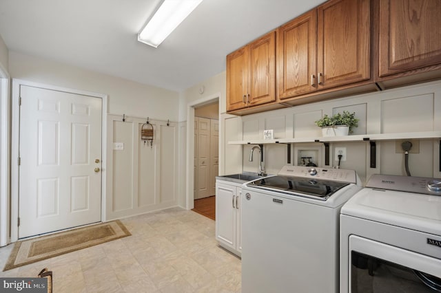 clothes washing area with cabinets, sink, and washer and clothes dryer