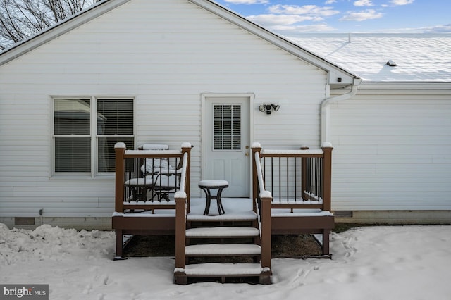 snow covered back of property with a deck