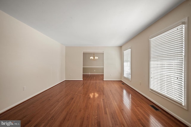 unfurnished room featuring wood-type flooring and an inviting chandelier