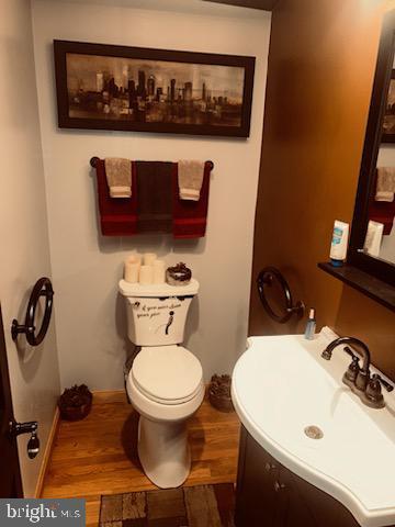 bathroom with wood-type flooring, toilet, and vanity