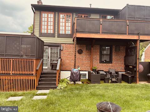 rear view of house with a lawn, an outdoor living space with a fire pit, and a deck