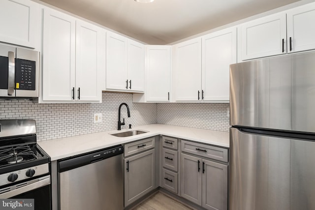 kitchen featuring appliances with stainless steel finishes, sink, gray cabinets, and white cabinetry