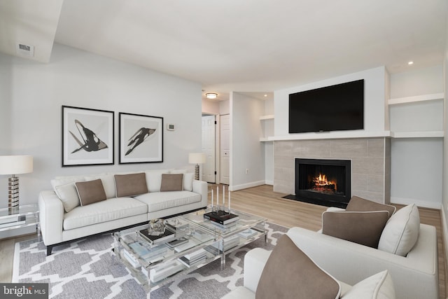 living room with light wood-type flooring and a tile fireplace