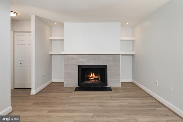 room details featuring hardwood / wood-style flooring, built in shelves, and a tile fireplace