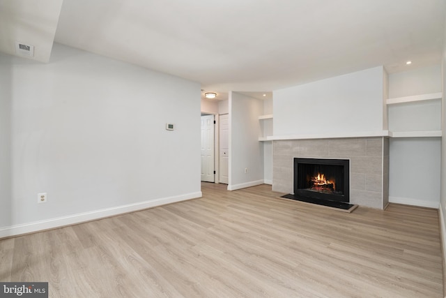 unfurnished living room featuring a fireplace and light hardwood / wood-style floors