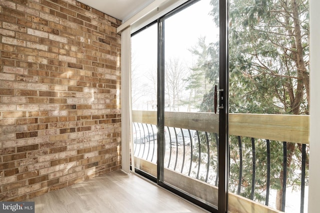 entryway with brick wall and light hardwood / wood-style floors