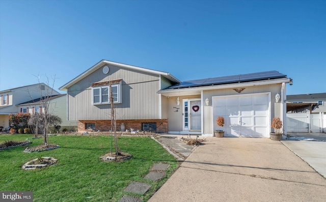 split level home with a garage, a front lawn, and solar panels