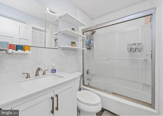 full bathroom featuring toilet, tile walls, backsplash, enclosed tub / shower combo, and vanity