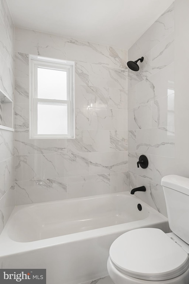 bathroom with toilet and tiled shower / bath