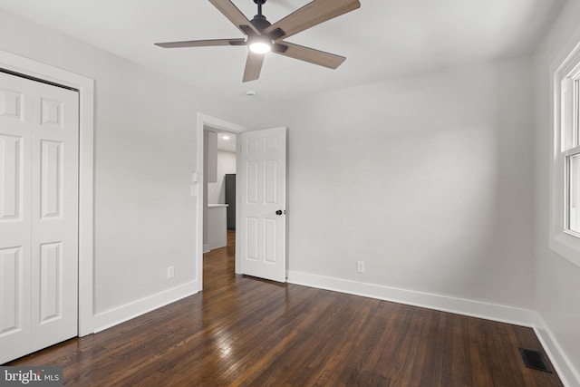 unfurnished bedroom featuring a closet, ceiling fan, and dark wood-type flooring