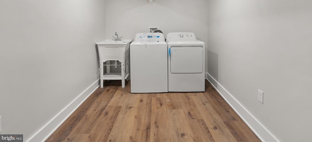 laundry room featuring washing machine and clothes dryer, light hardwood / wood-style flooring, and sink