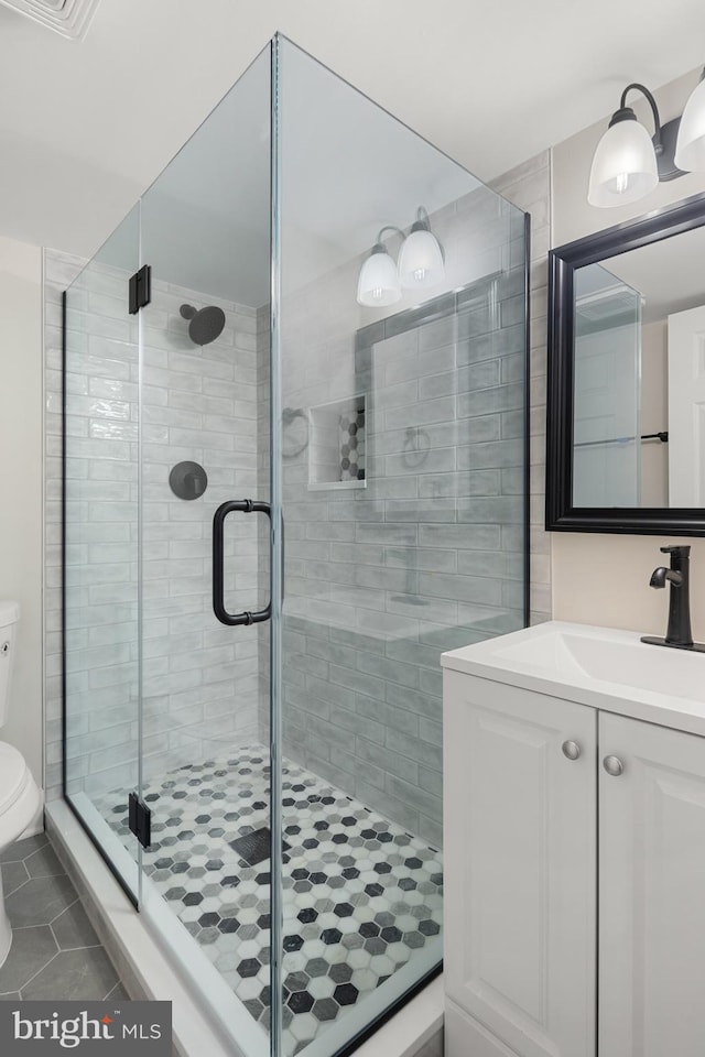 bathroom featuring tile patterned floors, vanity, toilet, and walk in shower