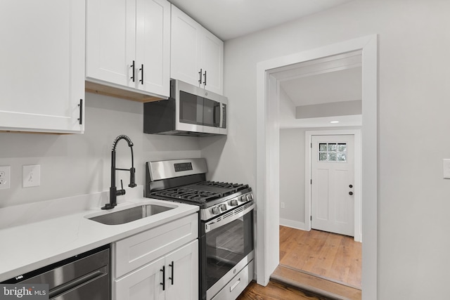 kitchen featuring hardwood / wood-style floors, stainless steel appliances, white cabinetry, and sink