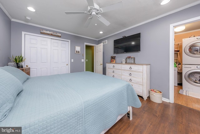 bedroom featuring ceiling fan, ornamental molding, dark wood-type flooring, and stacked washer and clothes dryer