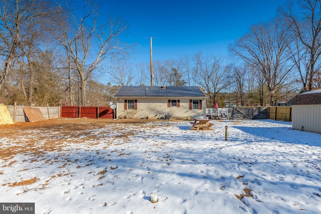 snow covered rear of property with solar panels, a trampoline, and a shed