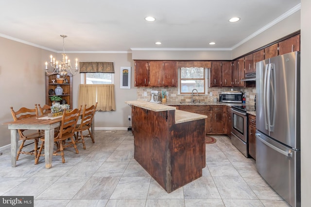 kitchen with appliances with stainless steel finishes, sink, pendant lighting, an inviting chandelier, and a kitchen island