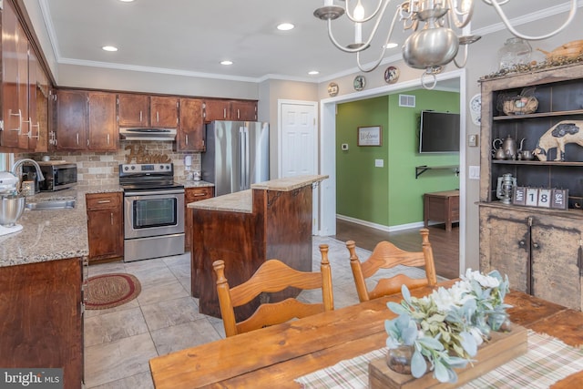 kitchen featuring sink, appliances with stainless steel finishes, decorative light fixtures, a kitchen island, and a chandelier