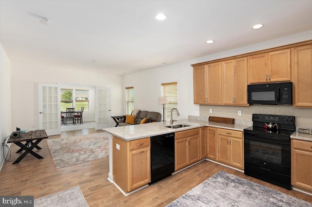 kitchen with kitchen peninsula, french doors, sink, black appliances, and light hardwood / wood-style flooring