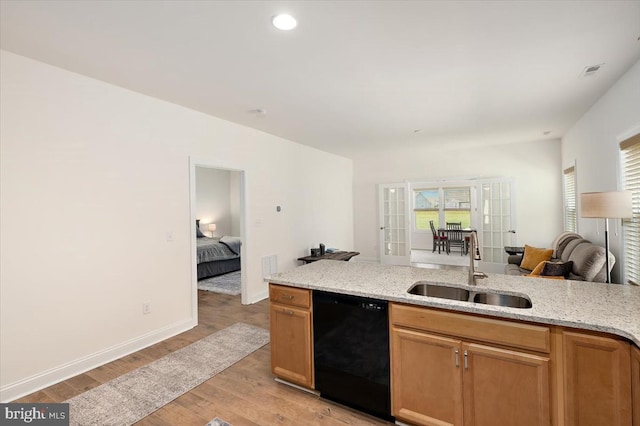 kitchen with light stone counters, dishwasher, light hardwood / wood-style flooring, and sink