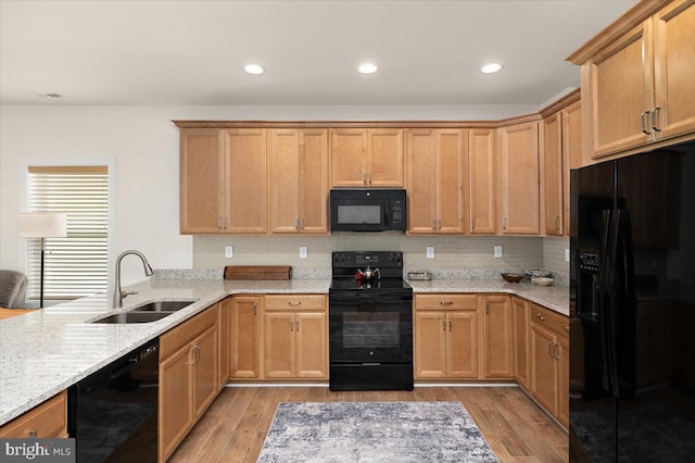 kitchen with light stone counters, sink, black appliances, and light wood-type flooring