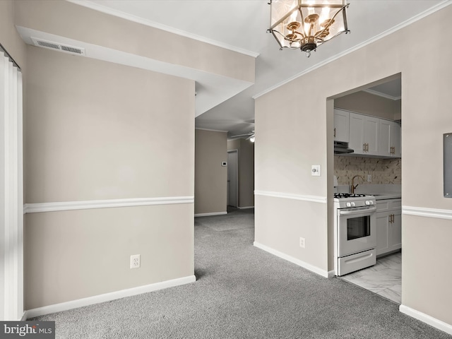 kitchen featuring tasteful backsplash, gas range gas stove, ceiling fan with notable chandelier, ventilation hood, and light colored carpet