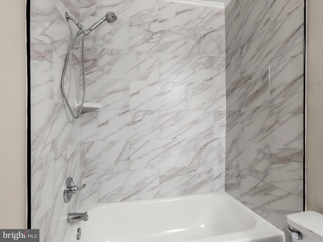 bathroom featuring toilet and tiled shower / bath