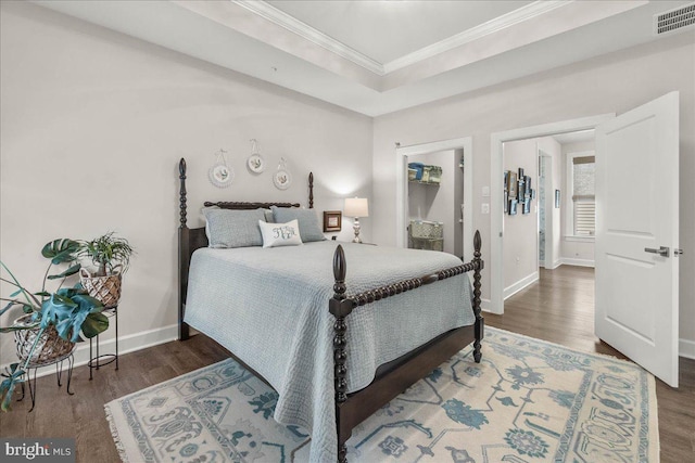 bedroom with a tray ceiling, crown molding, and dark wood-type flooring