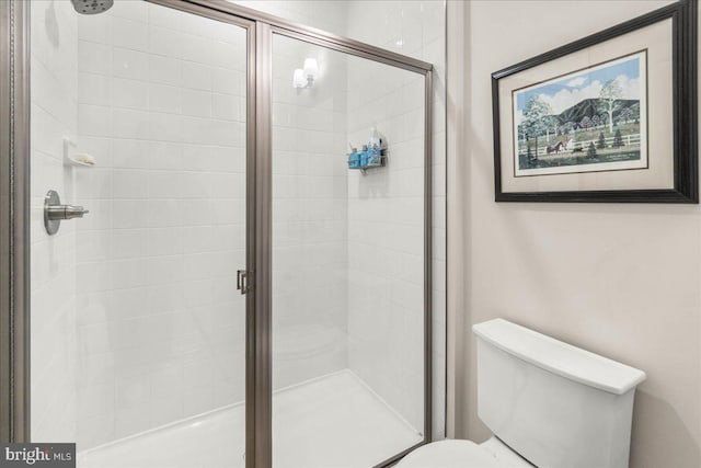 bathroom featuring toilet and a shower with shower door