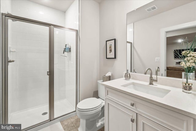 bathroom featuring tile patterned flooring, vanity, a shower with shower door, and toilet