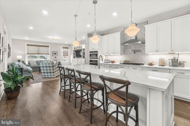 kitchen with a kitchen breakfast bar, a center island with sink, white cabinetry, and sink