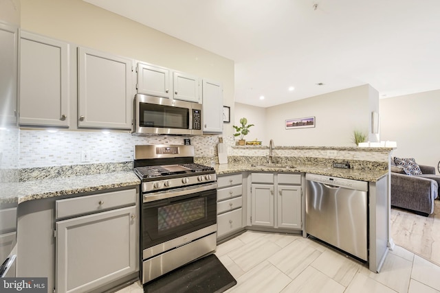 kitchen with sink, decorative backsplash, light tile patterned floors, appliances with stainless steel finishes, and kitchen peninsula