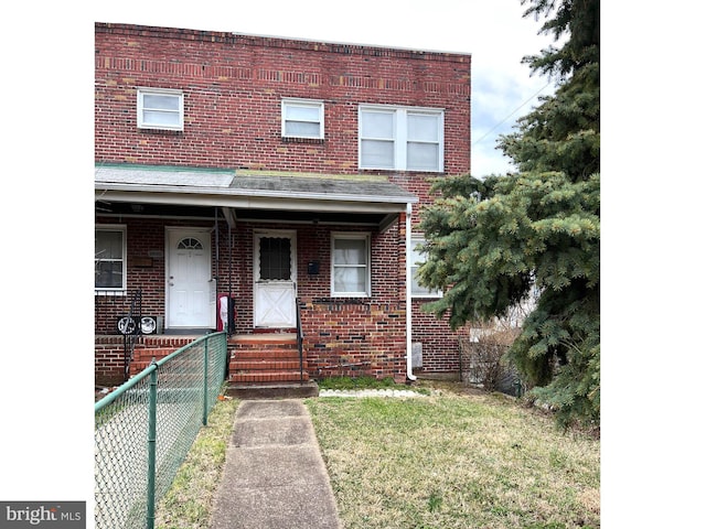 townhome / multi-family property with a front yard, fence, and brick siding