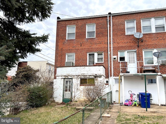 rear view of property featuring brick siding and fence