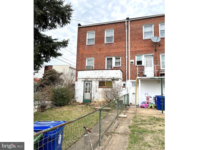 rear view of property featuring brick siding and fence