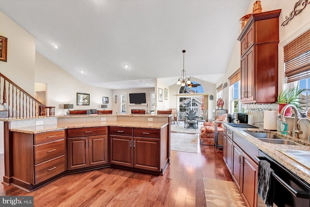 kitchen with pendant lighting, sink, hardwood / wood-style flooring, dishwasher, and light stone counters