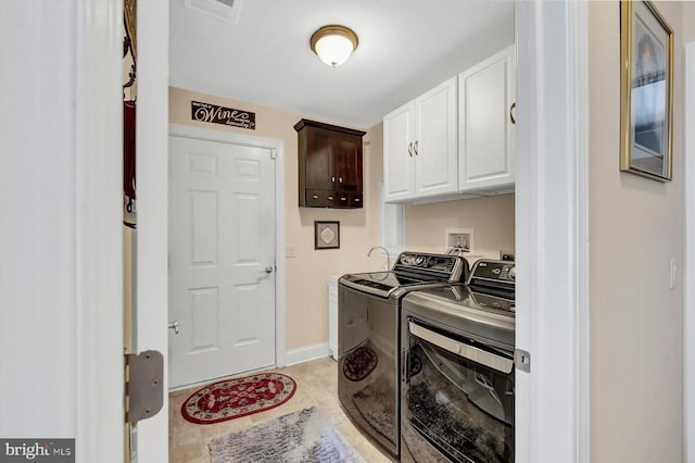 clothes washing area with cabinets, washing machine and dryer, and light tile patterned flooring