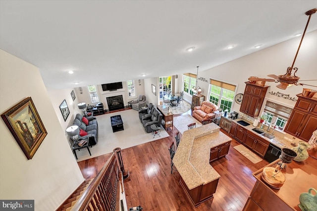 living room with ceiling fan, high vaulted ceiling, dark hardwood / wood-style floors, and sink