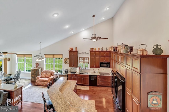 kitchen with ceiling fan with notable chandelier, light stone counters, light hardwood / wood-style floors, and black appliances