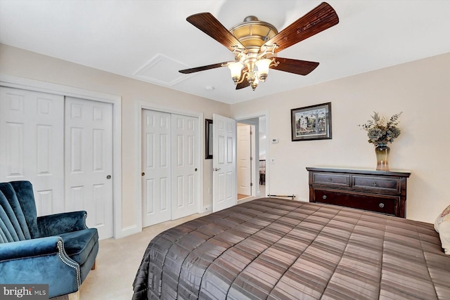 bedroom featuring multiple closets, light colored carpet, and ceiling fan