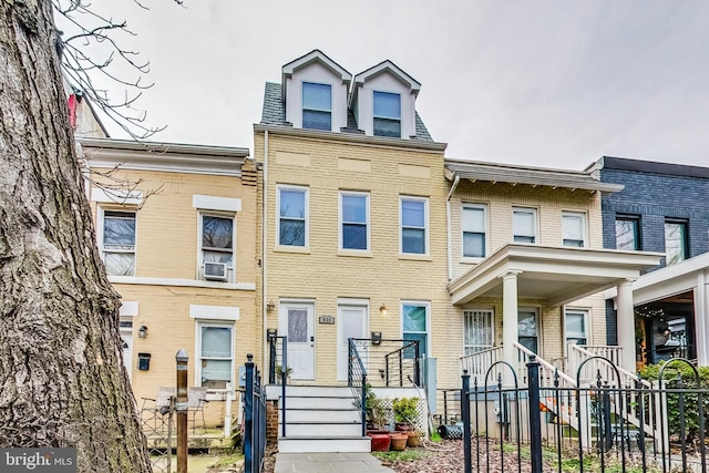 townhome / multi-family property featuring brick siding, cooling unit, and fence