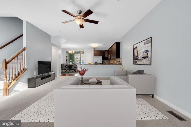 living room with light colored carpet and ceiling fan with notable chandelier